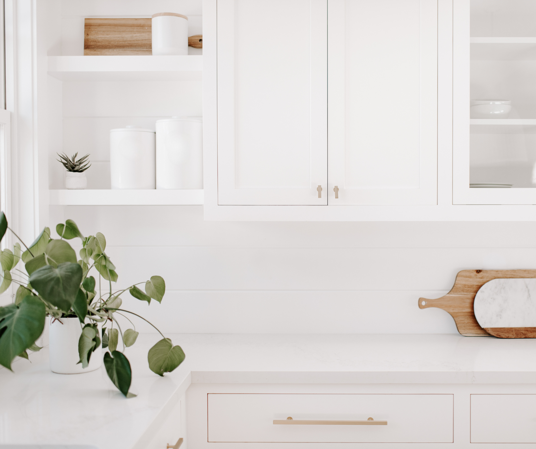 Cuisine blanche avec plante verte et planche en bois